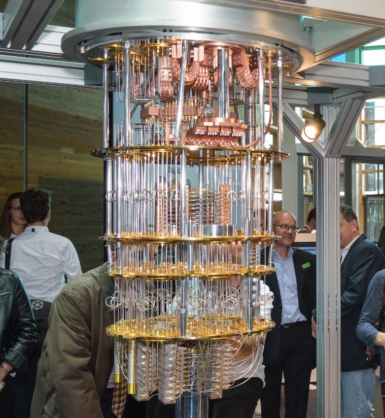 Picture of a Quantum Computer with people standing around it at an event.